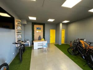 Bike rental shop interior with bicycles, safety helmets, and a modern reception area at KUDO Rent, offering easy access to e-bikes and mountain bikes for exploring the city or countryside.