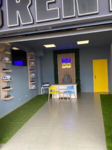 Modern indoor bike rental shop with Helmets on wall, colorful chairs, and sleek signage for KUDO Rent bike shop.