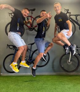 Bike rental shop KUDO Rent team jumping in front of bikes, showcasing fun and active cycling experience in a modern cycling store. Perfect for bike enthusiasts looking to rent quality bikes.