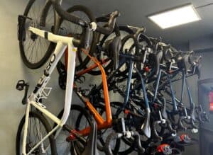 White and black road bikes mounted on a wall bike rack for rent at KUDO Rent.