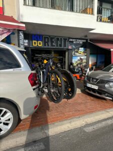 Electric bicycles mounted on car at KUDO Rent bike shop in Tenerife, offering bike rentals for outdoor adventures and mountain biking.