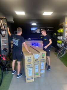 High-quality bicycle delivery at KUDO Rent bike shop, with staff unpacking new bikes in a modern, well-organized bike shop equipped with helmets, bikes, and accessories for cycling enthusiasts.