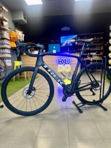 High-performance Trek road bike displayed indoors at KUDO Rent with sleek black frame, carbon wheels, and advanced gear system, ideal for cycling enthusiasts and urban riders seeking quality rental bikes.
