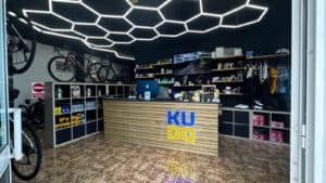 High-tech bicycle shop interior with a modern LED ceiling design, featuring bike accessories, sports clothing, and repair equipment at KUDO Rent.